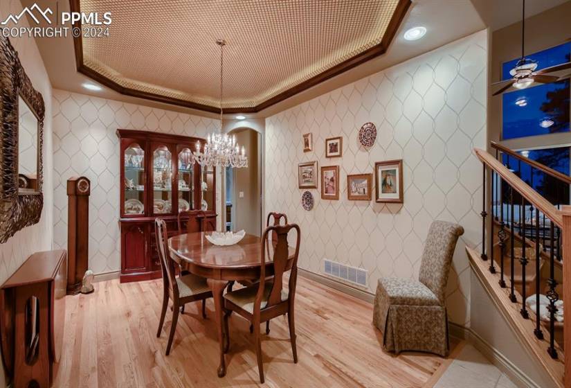 Dining area featuring light hardwood floors, a tray ceiling, with notable chandelier