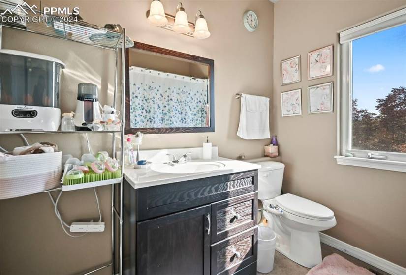 Bathroom with a wealth of natural light, large vanity, tile flooring, and toilet