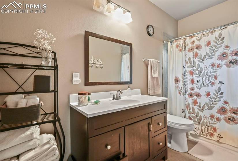 Bathroom with toilet, vanity with extensive cabinet space, and tile flooring