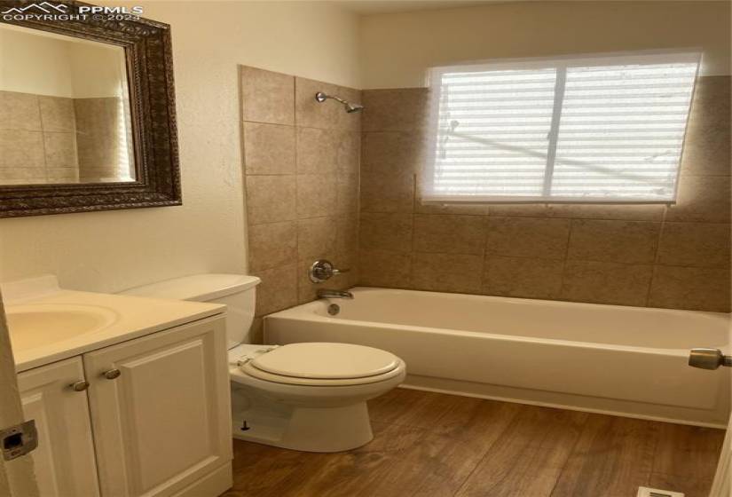 Upper Bath Full bathroom with vanity, toilet, tiled shower / bath combo, and hardwood / wood-style flooring