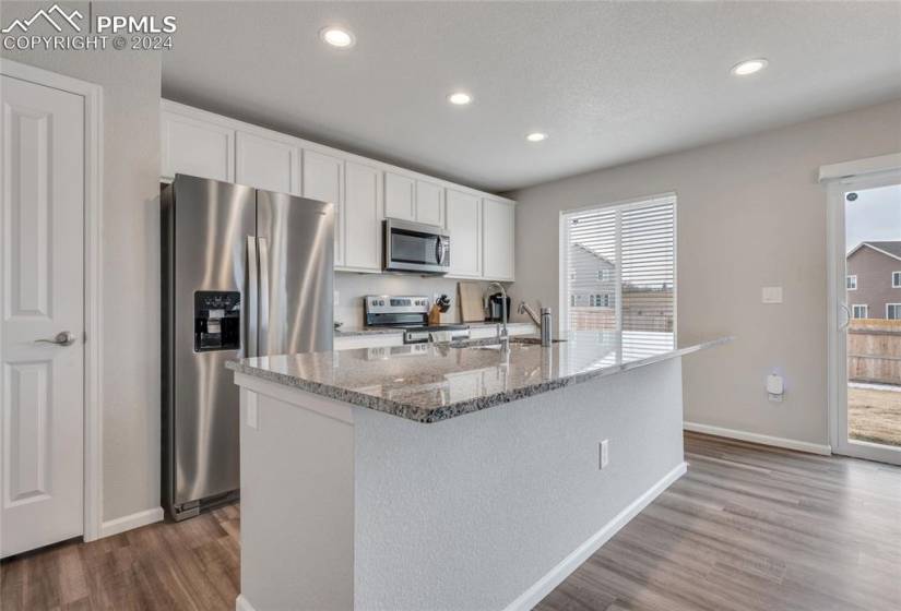 Kitchen with white cabinets, a wealth of natural light, dark hardwood / wood-style floors, and appliances with stainless steel finishes