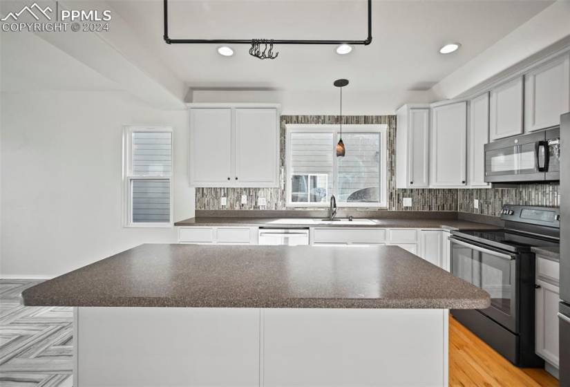 Kitchen featuring white cabinetry, backsplash, electric range, sink, and a center island