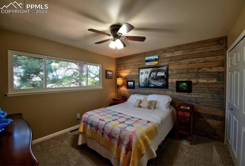 Bedroom with ceiling fan, dark carpet, and a closet