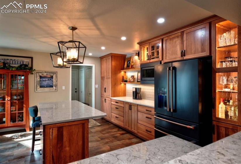 Kitchen featuring backsplash, dark wood-type flooring, a notable chandelier, pendant lighting, and high quality fridge