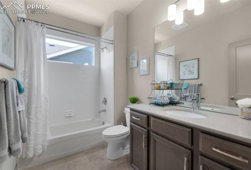 Full bathroom featuring tub/shower combo, tile floors, and toilet