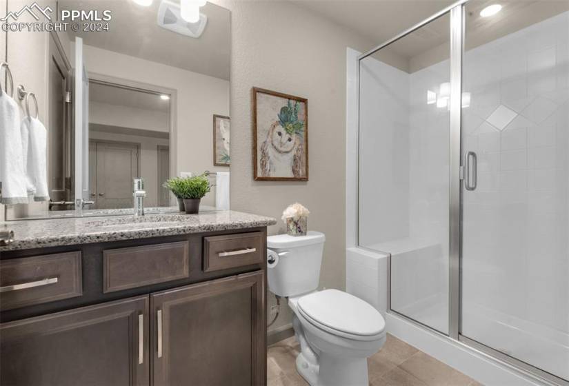 Jr Master Bathroom featuring vanity, toilet, a shower with door, and tile floors