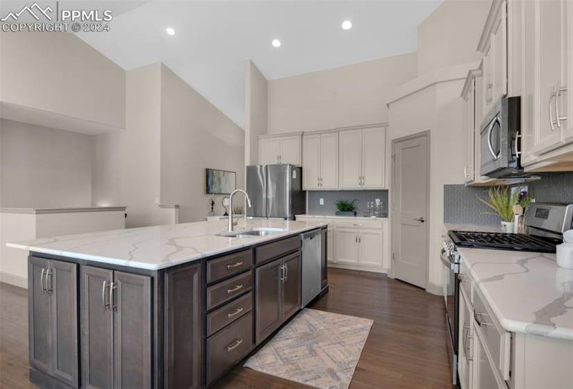 Kitchen featuring backsplash, grey cabinetry, sink, an island with sink, and stainless steel appliances