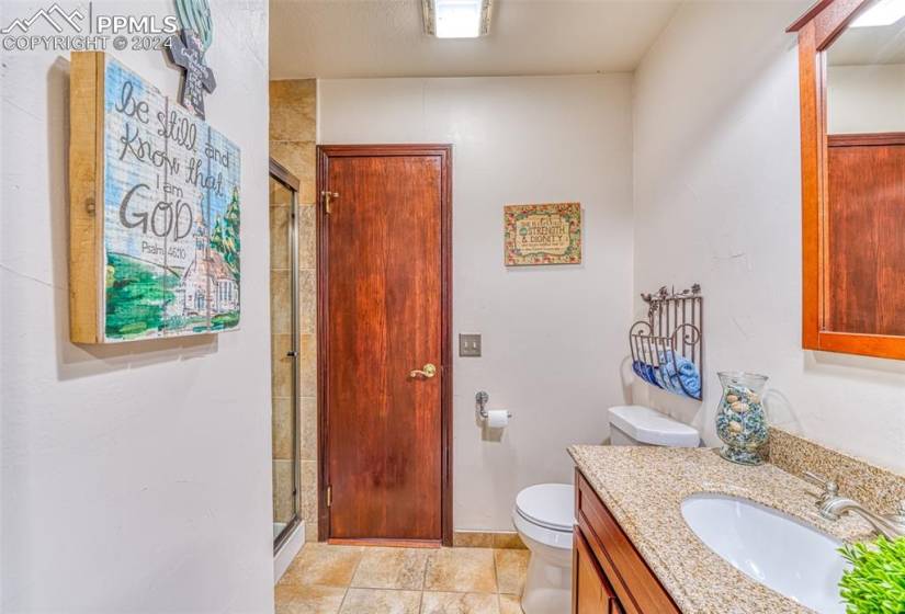 Bathroom featuring a shower with door, toilet, tile floors, and vanity with extensive cabinet space