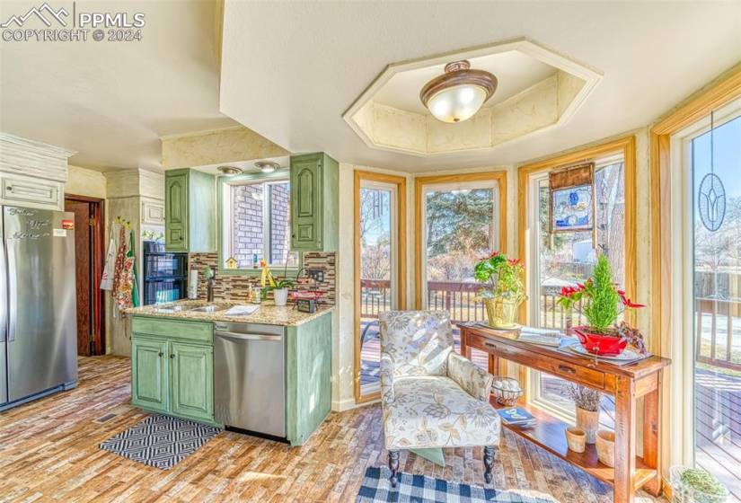 Kitchen featuring green cabinets, stainless steel appliances, backsplash, and sink
