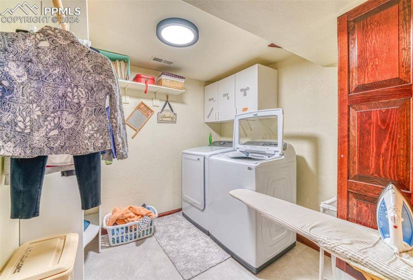 Laundry area with cabinets, light tile flooring, and separate washer and dryer