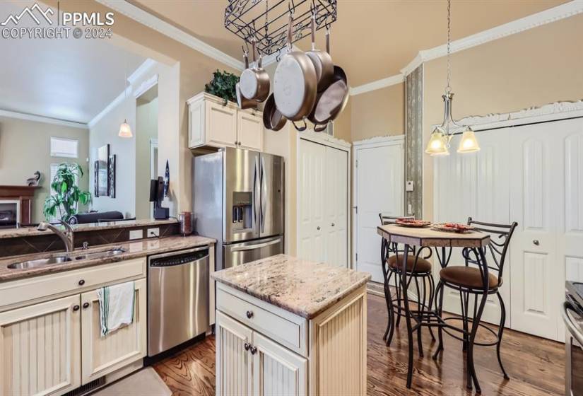 Kitchen with a kitchen island, appliances with stainless steel finishes, crown molding, sink, and dark hardwood / wood-style floors
