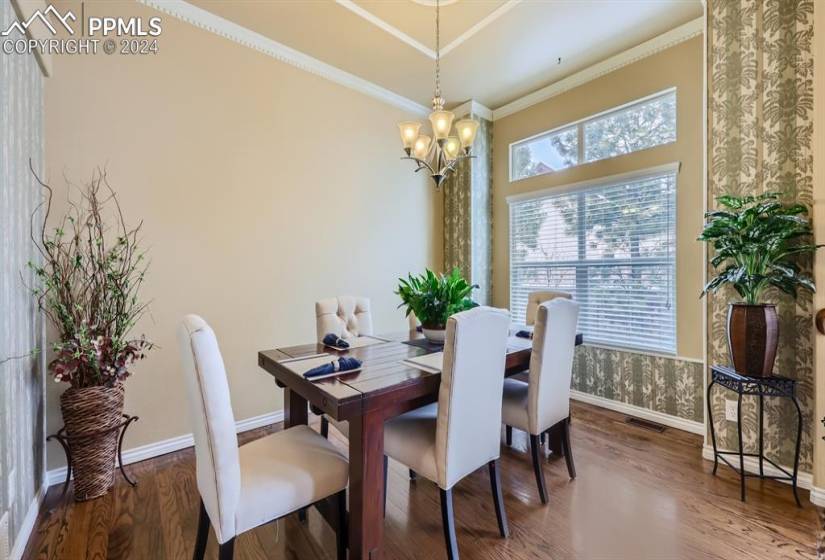 Dining space featuring dark wood-type flooring, an inviting chandelier, and crown molding
