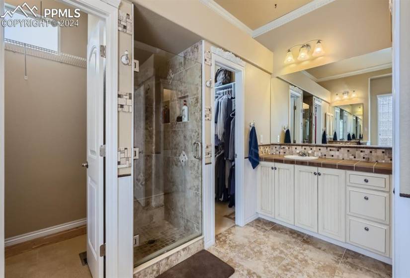 Bathroom with vanity, a shower with door, tile floors, and ornamental molding