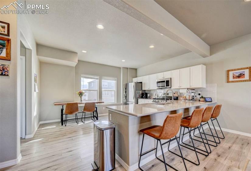 Kitchen with stainless steel appliances, white cabinets, breakfast bar