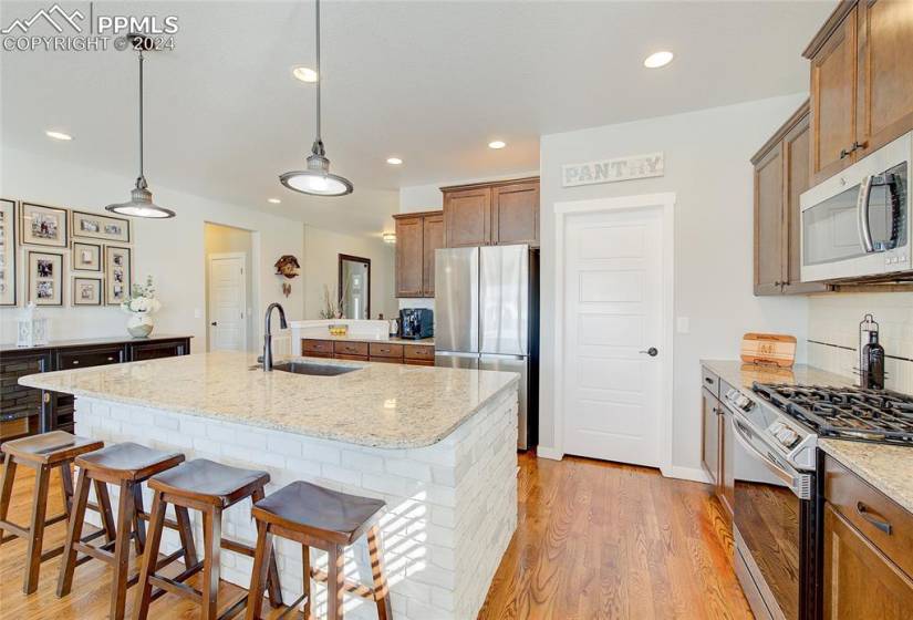 Kitchen Island/bar, light  countertops, appliances with stainless steel finishes, and sink