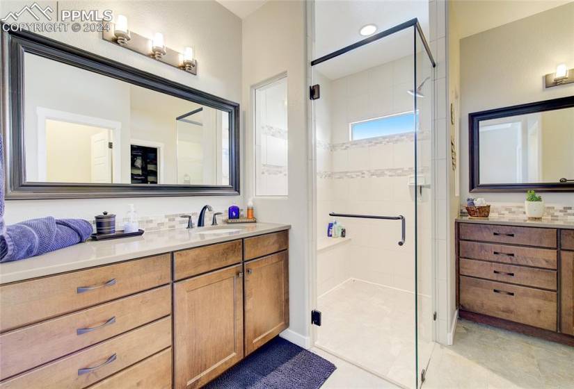 Bathroom featuring glass shower doors, tile floors, and double vanity