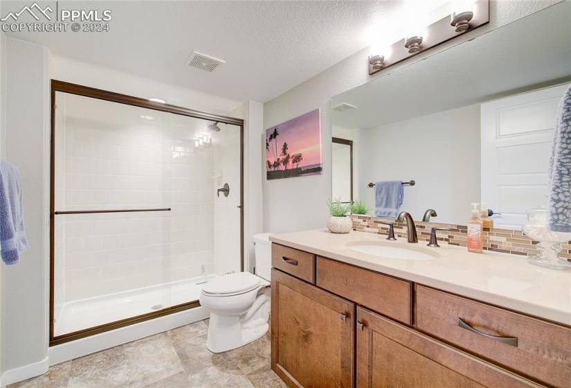 Bathroom with large vanity, walk in shower, and tile flooring