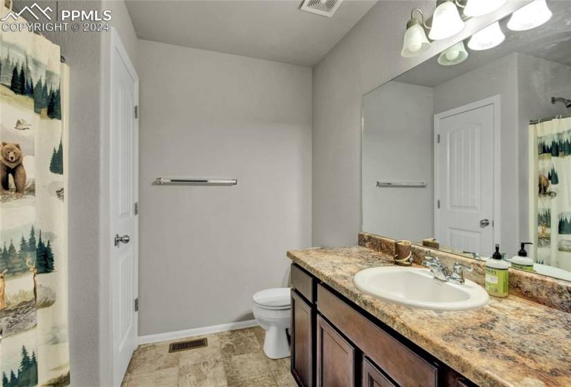 Full upper-level hall bathroom with extensive vanity cabinet space and linen closet