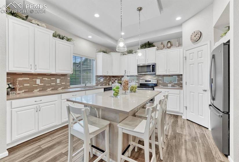 Kitchen with a kitchen island, appliances with stainless steel finishes, backsplash, and white cabinets