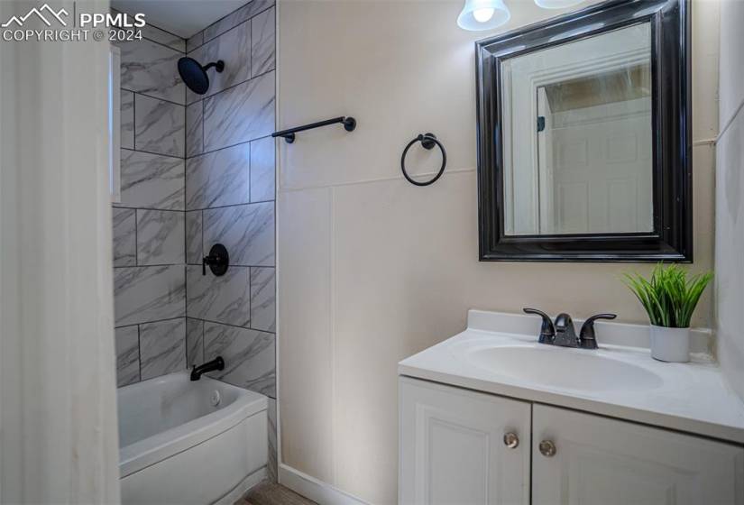 Bathroom featuring large vanity and tiled shower / bath