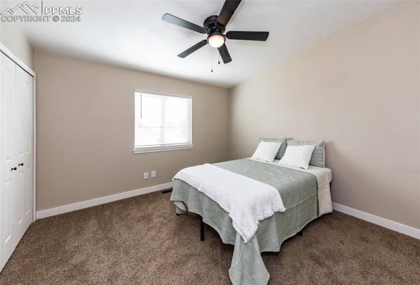 Carpeted bedroom featuring ceiling fan and a closet