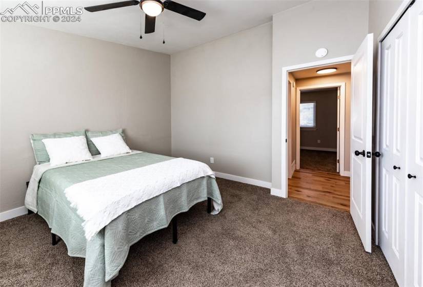 Carpeted bedroom featuring ceiling fan and a closet