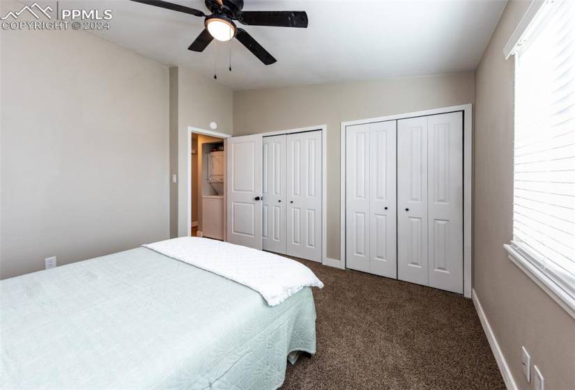 Bedroom featuring ceiling fan, multiple closets, vaulted ceiling, and dark carpet