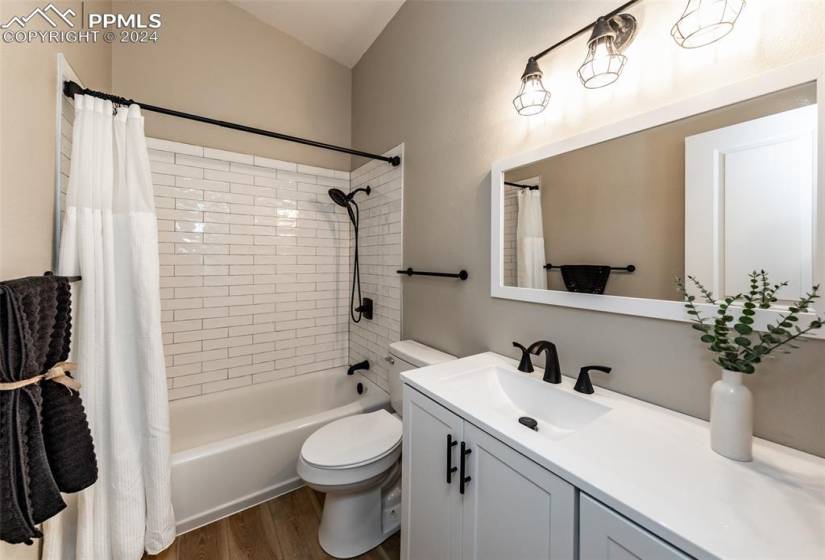 Full bathroom featuring shower / bathtub combination with curtain, toilet, hardwood / wood-style flooring, and oversized vanity