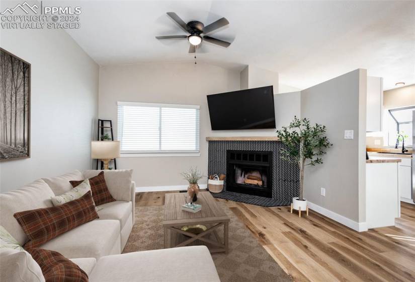 Virtually Staged Living room with a tile fireplace, light wood-type flooring, vaulted ceiling, and ceiling fan