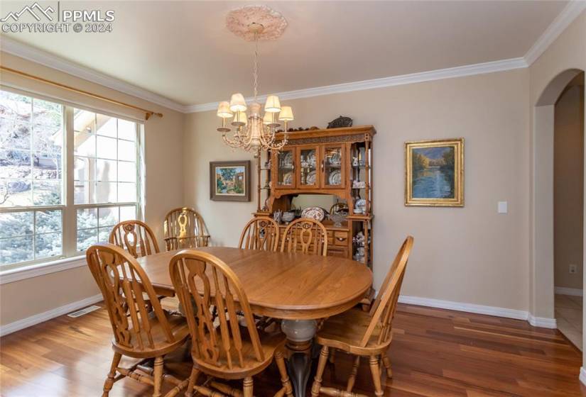 Dining area with a notable chandelier, dark hardwood / wood-style flooring, and crown molding