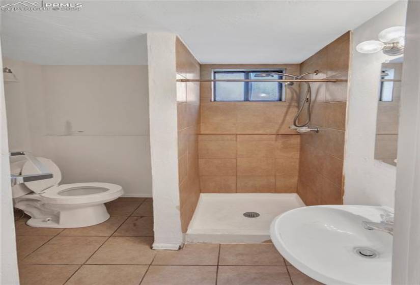 Bathroom featuring sink, tiled shower, tile floors, and toilet