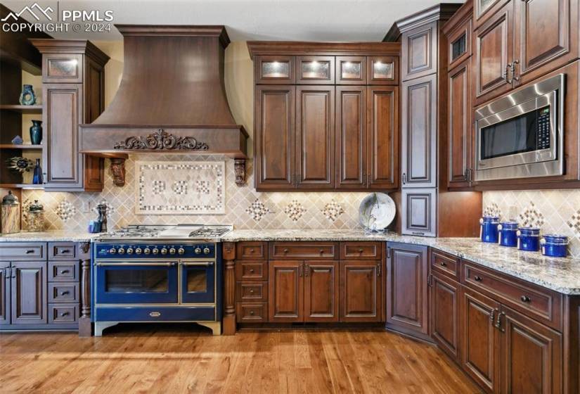 Kitchen with range with two ovens, light hardwood / wood-style floors, premium range hood, and tasteful backsplash