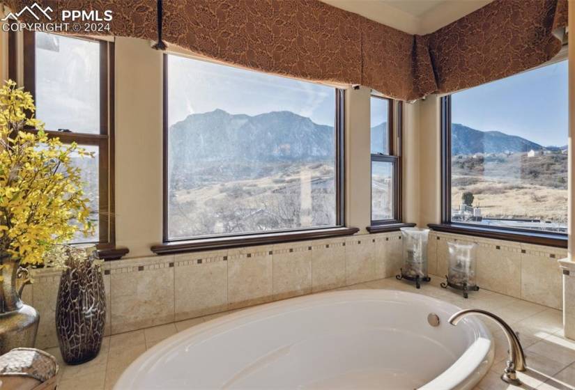 Bathroom with plenty of natural light, a relaxing tiled bath, and a mountain view