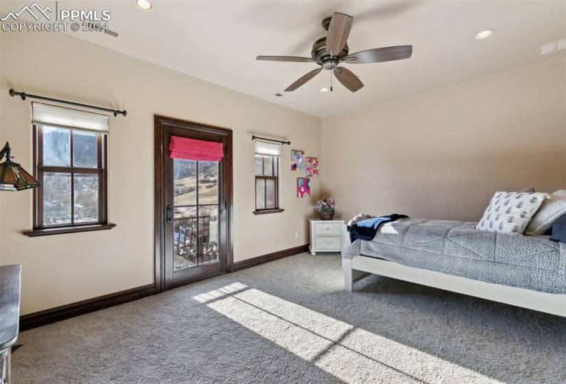 Bedroom featuring ceiling fan, dark carpet, and access to exterior