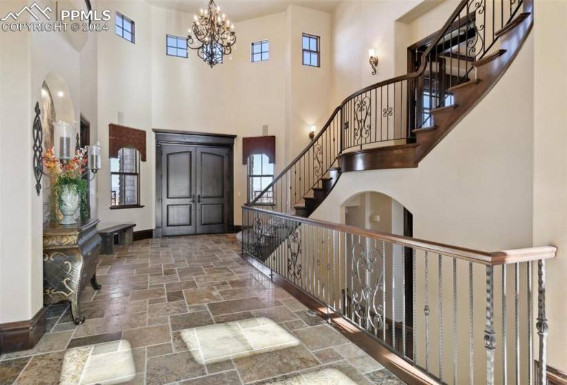 Tiled foyer entrance with an inviting chandelier and a towering ceiling