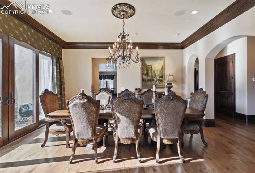 Dining space with light hardwood / wood-style flooring, ornamental molding, and a notable chandelier
