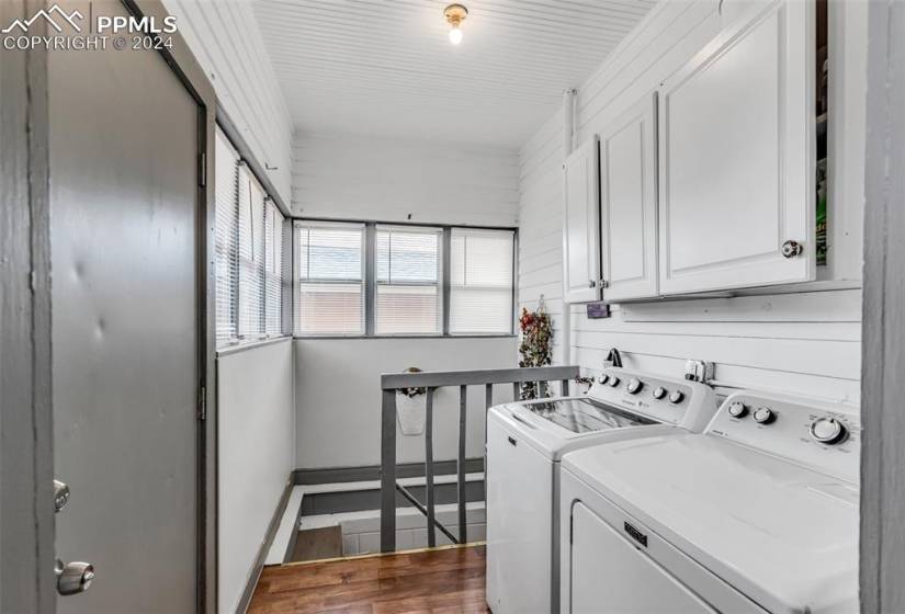 Laundry room with cabinets, dark hardwood / wood-style flooring, and washer and clothes dryer