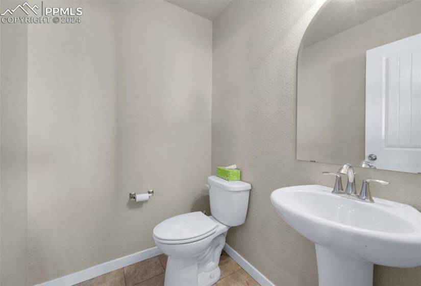 Bathroom featuring toilet, sink, and tile floors