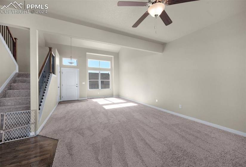 Unfurnished living room featuring dark colored carpet and ceiling fan