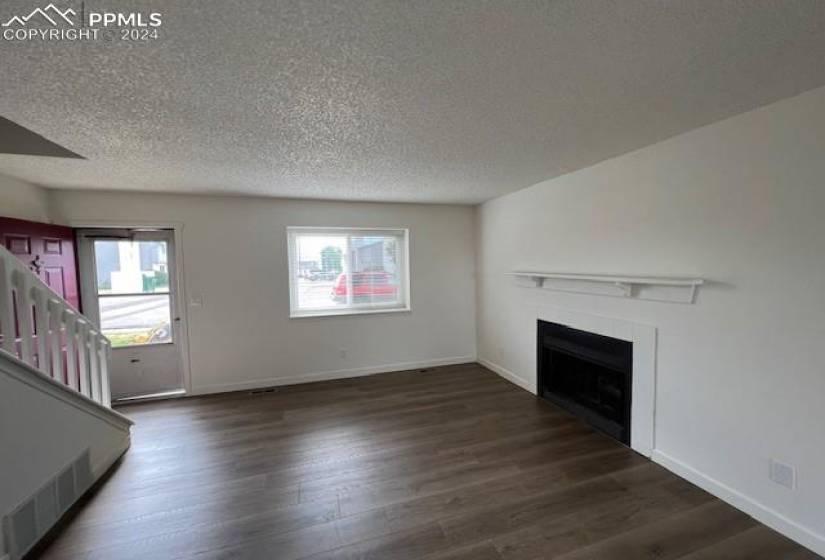 Unfurnished living room featuring dark hardwood / wood-style floors and a textured ceiling