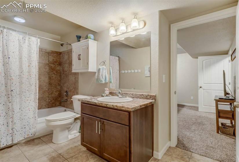 Full bathroom with shower / bathtub combination with curtain, a textured ceiling, toilet, large vanity, and tile flooring