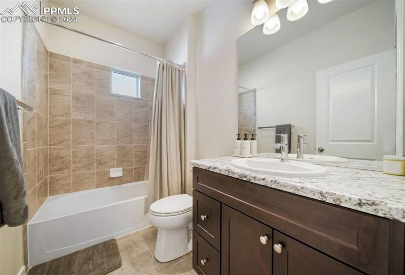 Full bathroom featuring toilet, shower / bath combo with shower curtain, tile floors, and oversized vanity