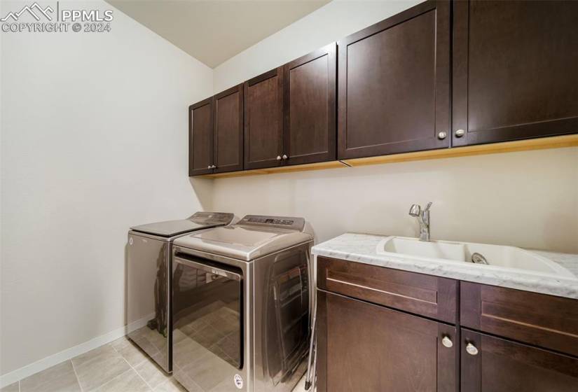 Laundry room featuring cabinets, sink, washing machine and dryer, and light tile floors
