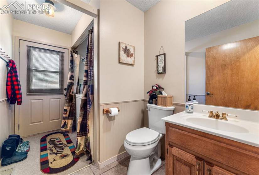 Bathroom with toilet, vanity with extensive cabinet space, tile flooring, and a textured ceiling