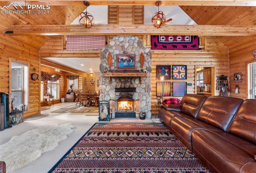 Carpeted living room with wooden ceiling, a fireplace, beam ceiling, and rustic walls