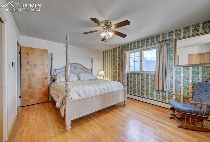 Bedroom featuring light hardwood / wood-style flooring, a baseboard heating unit, and ceiling fan
