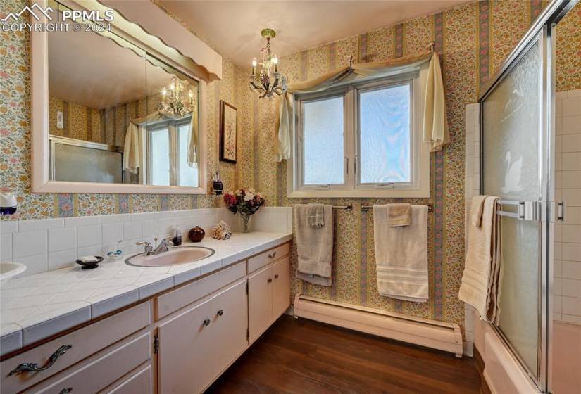 Bathroom with a chandelier, hardwood / wood-style flooring, a baseboard radiator, and vanity
