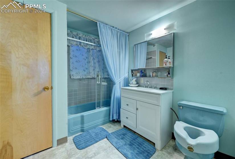 Full bathroom featuring shower / bath combo with shower curtain, backsplash, vanity with extensive cabinet space, toilet, and tile flooring
