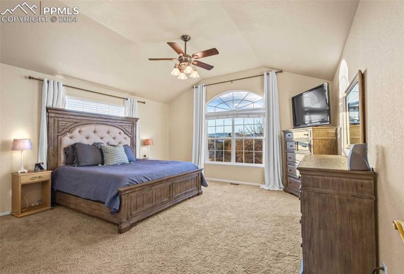 Bedroom featuring light carpet, ceiling fan, and vaulted ceiling