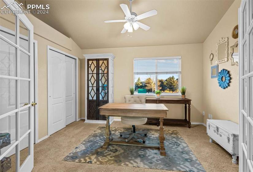 Carpeted home office featuring ceiling fan and french doors
